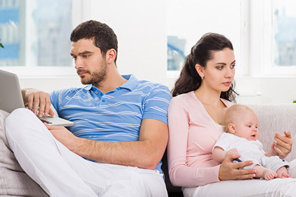 unhappy couple on electronic devices, with baby
